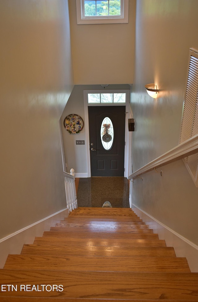 foyer entrance featuring stairs, a high ceiling, and baseboards