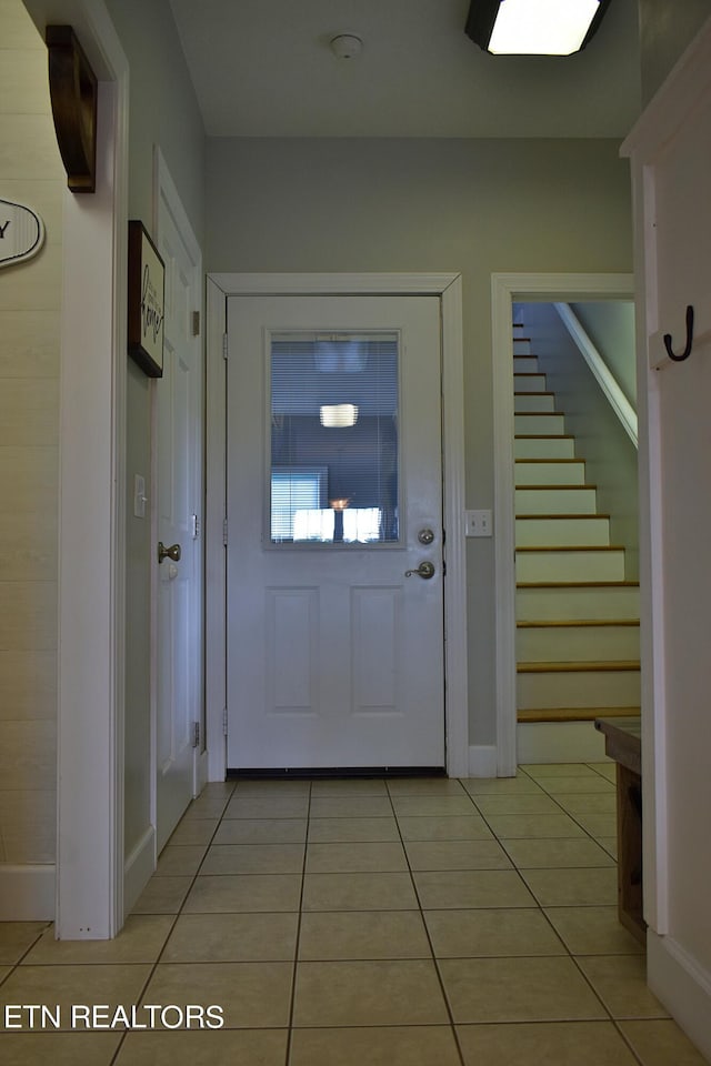 foyer featuring stairs, baseboards, and light tile patterned floors