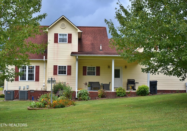 rear view of house with a yard, a shingled roof, and central air condition unit