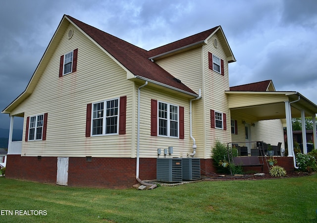 rear view of property featuring a yard, a porch, and central air condition unit