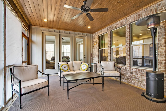 sunroom with wooden ceiling, a wood stove, and ceiling fan