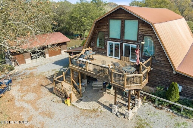 back of property featuring a deck, an outdoor structure, a patio, and a garage