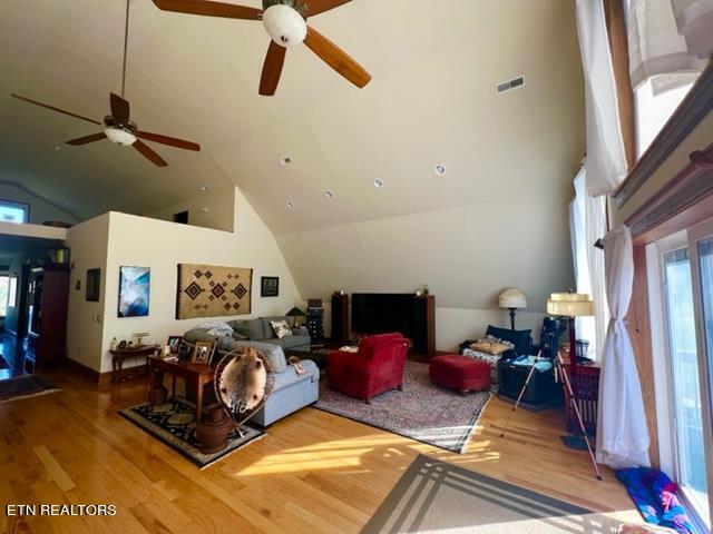 living room with high vaulted ceiling, ceiling fan, and light hardwood / wood-style flooring