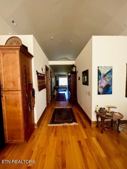 hall with dark hardwood / wood-style flooring and vaulted ceiling