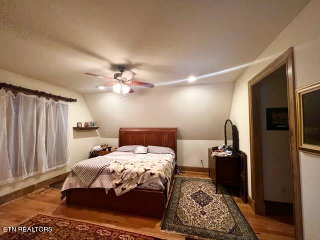 bedroom featuring lofted ceiling, wood-type flooring, and ceiling fan