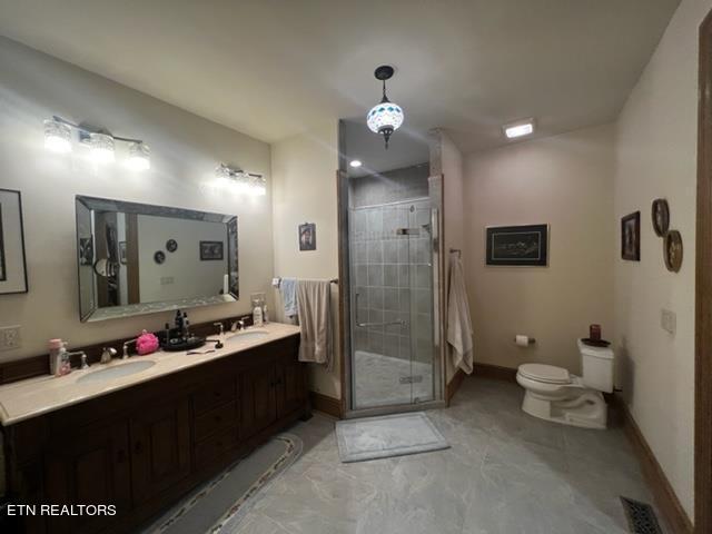 bathroom featuring dual sinks, toilet, a shower with door, large vanity, and tile floors