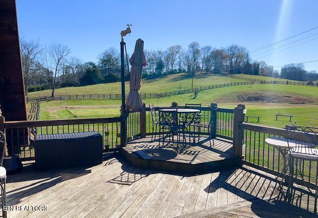 wooden deck with a rural view and a yard