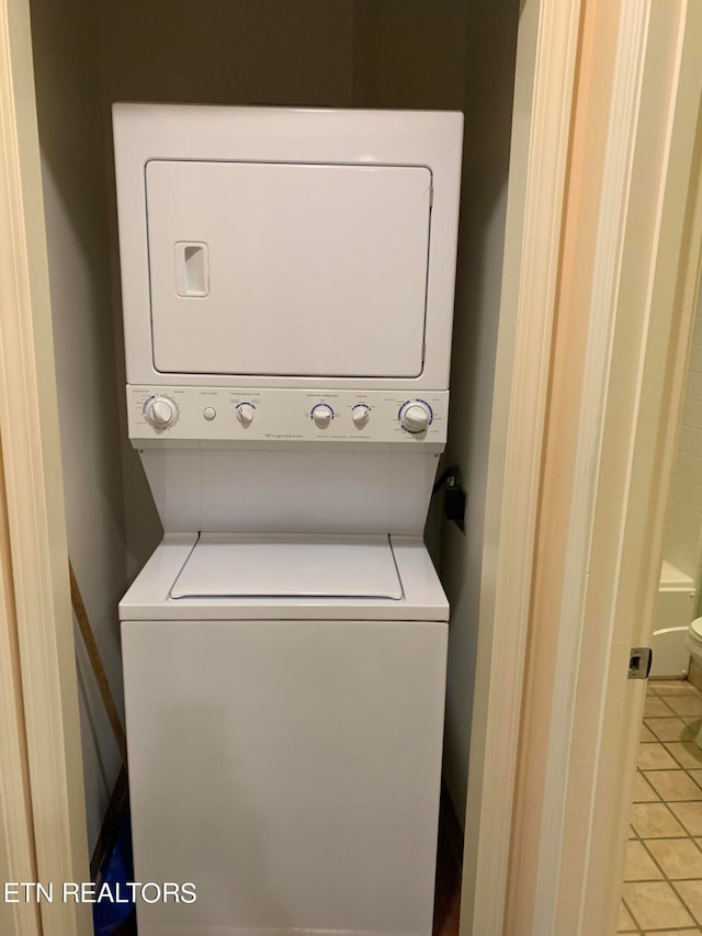 washroom with light tile floors and stacked washer / drying machine