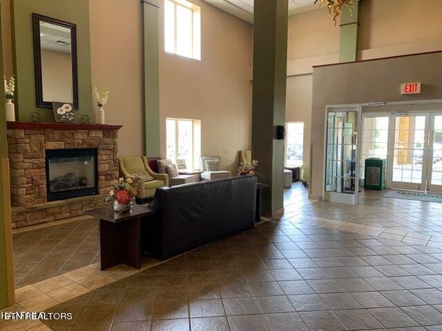 living room featuring a high ceiling, a fireplace, light tile floors, and a wealth of natural light