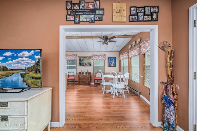 dining room featuring vaulted ceiling with beams, a baseboard radiator, ceiling fan, and light wood-type flooring