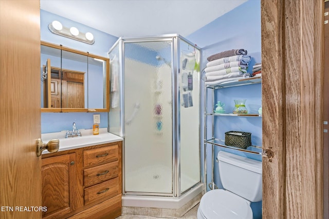 bathroom featuring toilet, vanity, and a shower with door