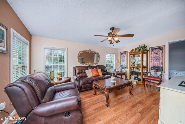 living room featuring ceiling fan, light hardwood / wood-style floors, and a textured ceiling