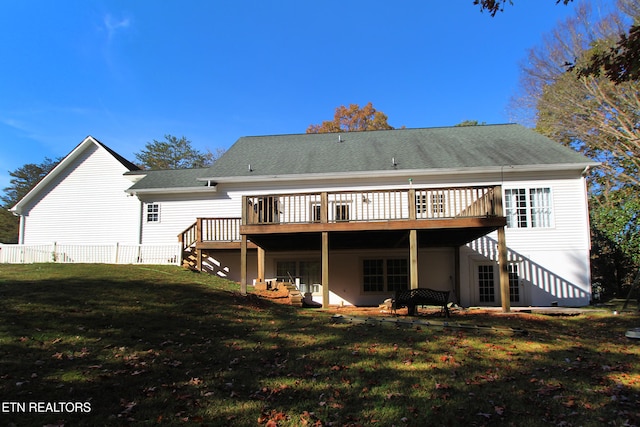 rear view of house with a wooden deck and a lawn