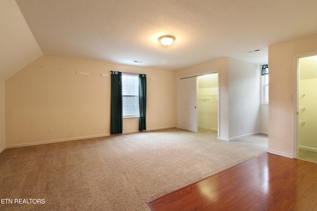 empty room featuring plenty of natural light, light hardwood / wood-style floors, and vaulted ceiling