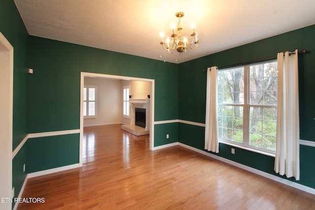 spare room with an inviting chandelier and hardwood / wood-style flooring