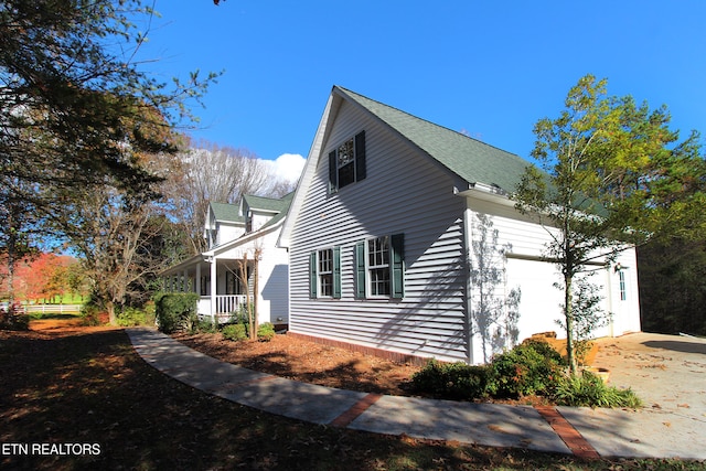 view of side of home featuring a garage and covered porch