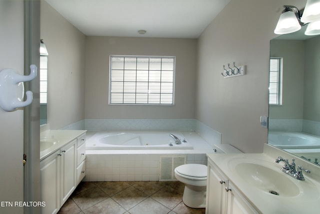 bathroom with vanity, toilet, tile patterned flooring, and tiled tub