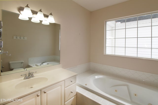 bathroom featuring a relaxing tiled tub, vanity, and toilet