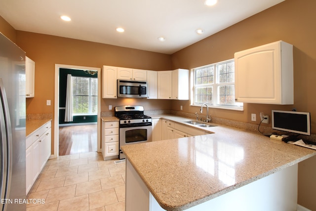 kitchen with white cabinetry, appliances with stainless steel finishes, sink, and kitchen peninsula