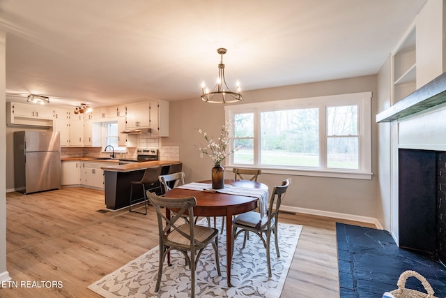 dining space featuring light wood-type flooring, a notable chandelier, and sink