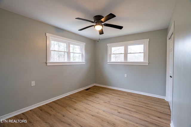 empty room featuring ceiling fan, a wealth of natural light, and light hardwood / wood-style floors