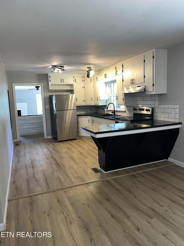 kitchen with kitchen peninsula, stainless steel appliances, and white cabinets