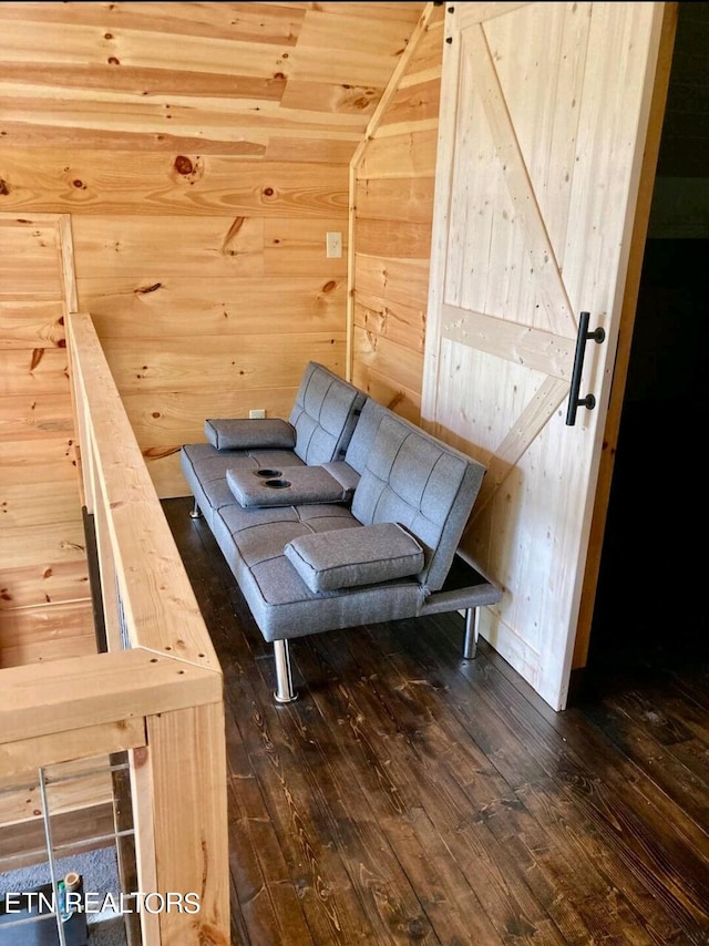 interior space featuring wood walls, a barn door, and dark hardwood / wood-style floors