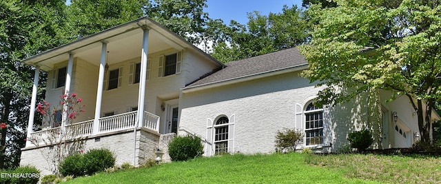 view of side of home with covered porch and a lawn