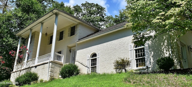 view of side of home with a porch and a yard