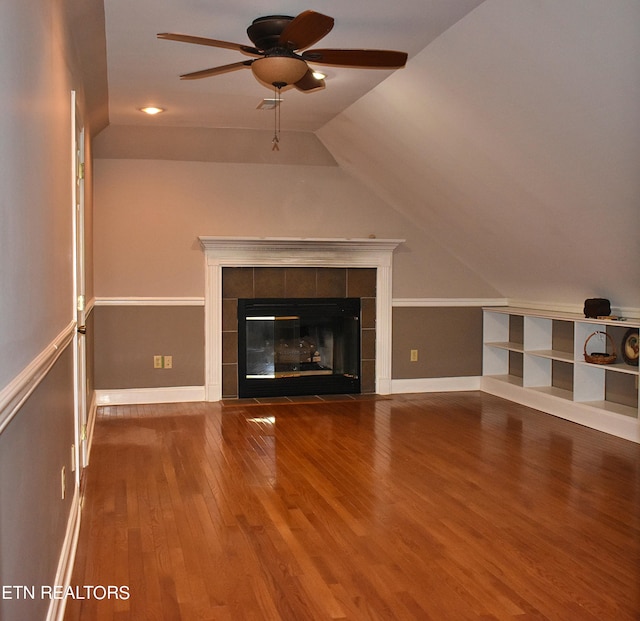 unfurnished living room featuring a tiled fireplace, wood-type flooring, lofted ceiling, and ceiling fan