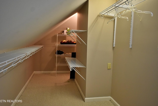 walk in closet with light carpet and vaulted ceiling