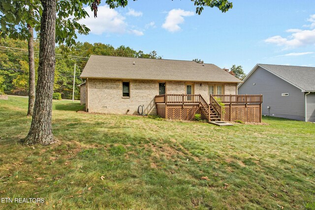 rear view of property featuring a wooden deck and a yard