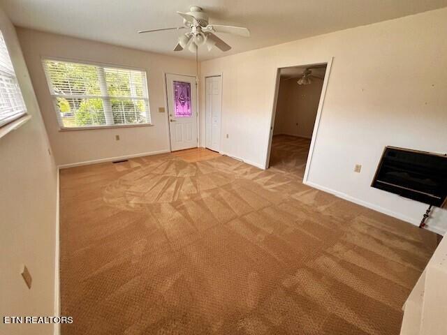 empty room featuring ceiling fan, carpet, and heating unit