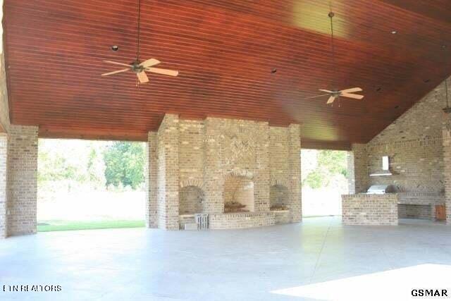 view of patio featuring ceiling fan, exterior kitchen, and exterior fireplace