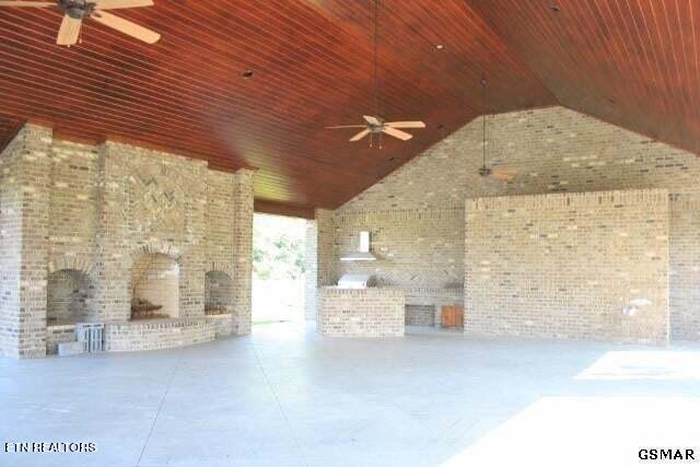 view of patio / terrace with an outdoor fireplace, exterior kitchen, and ceiling fan