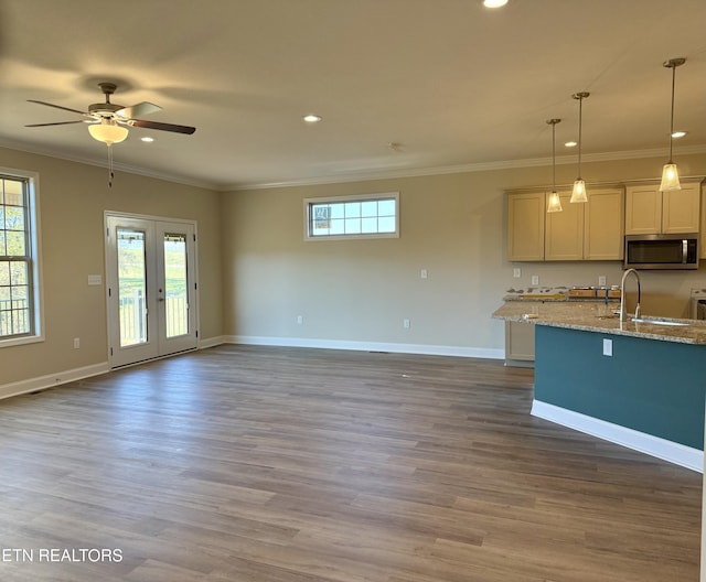 kitchen with decorative light fixtures, light stone countertops, a wealth of natural light, sink, and ornamental molding