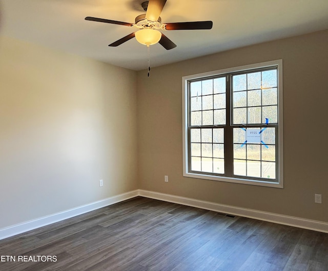 empty room with a healthy amount of sunlight, dark hardwood / wood-style flooring, and ceiling fan