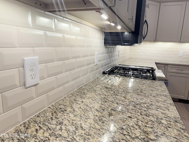 kitchen featuring gray cabinets, range, light stone countertops, and decorative backsplash