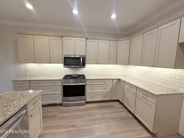 kitchen featuring light hardwood / wood-style floors, appliances with stainless steel finishes, light stone countertops, and ornamental molding