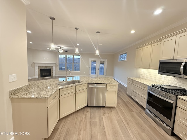 kitchen with appliances with stainless steel finishes, sink, cream cabinetry, and light stone countertops