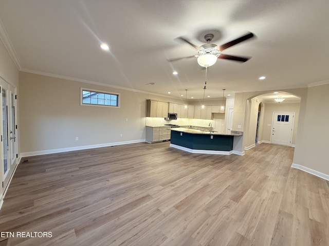 kitchen with a center island with sink, light hardwood / wood-style floors, ceiling fan, hanging light fixtures, and ornamental molding