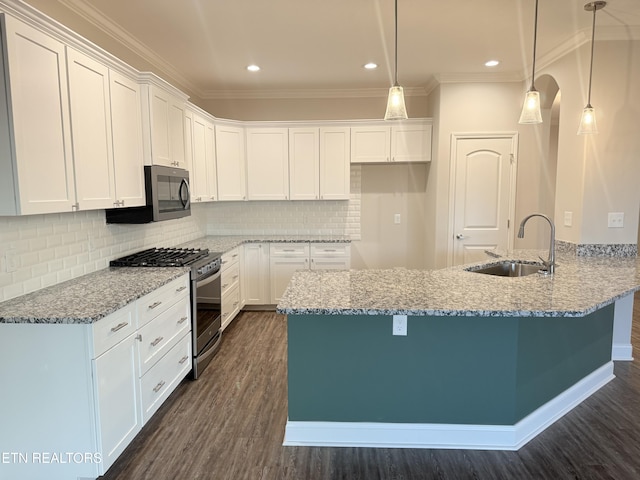 kitchen featuring dark wood-type flooring, stainless steel appliances, decorative light fixtures, sink, and white cabinetry