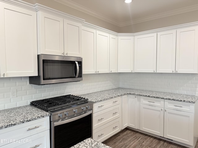 kitchen with stainless steel appliances, white cabinetry, and light stone countertops