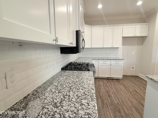 kitchen featuring white cabinetry, stainless steel range, ornamental molding, tasteful backsplash, and light stone counters