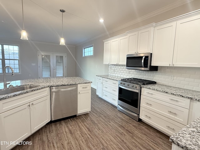 kitchen with sink, appliances with stainless steel finishes, white cabinets, and decorative light fixtures