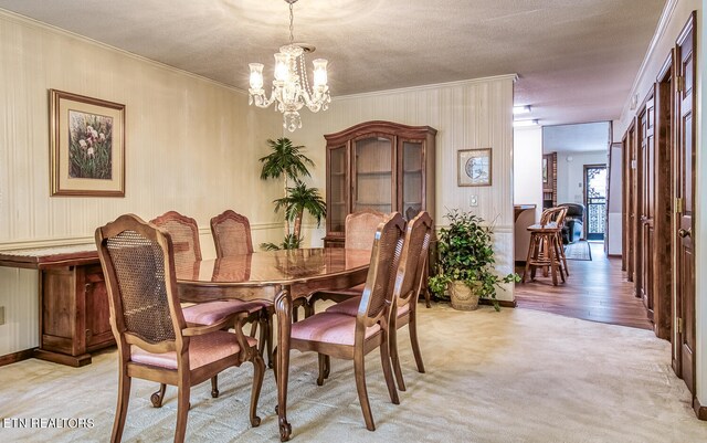 carpeted dining area with crown molding, a textured ceiling, and an inviting chandelier