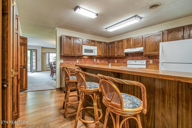 kitchen featuring range, kitchen peninsula, light wood-type flooring, a textured ceiling, and ornamental molding