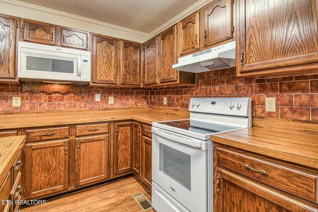 kitchen with butcher block counters, light hardwood / wood-style floors, a textured ceiling, white appliances, and ornamental molding