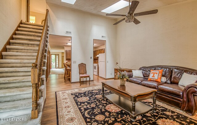 living room featuring ceiling fan, light hardwood / wood-style floors, and a skylight