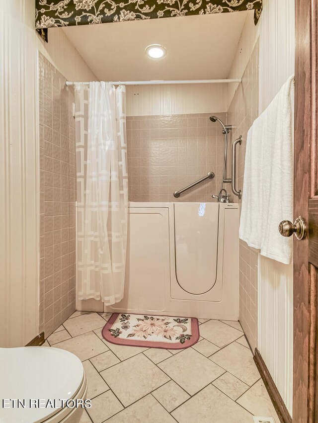 bathroom with tile patterned floors, shower / bath combination with curtain, tile walls, and toilet